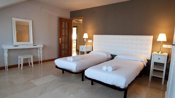 Habitación de hotel con dos camas, un escritorio, una silla y un espejo.