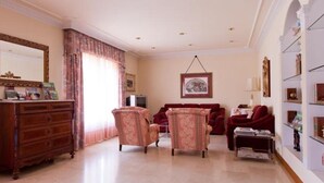 Un salón espacioso con un espejo grande, dos sillones, un sofá y una estantería.