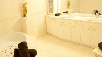 Un baño con bañera, dos lavamanos, un espejo grande y una estatua.