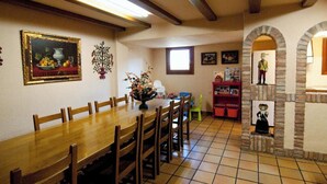 Un comedor con una mesa y sillas de madera, un cuadro y suelo de baldosas.
