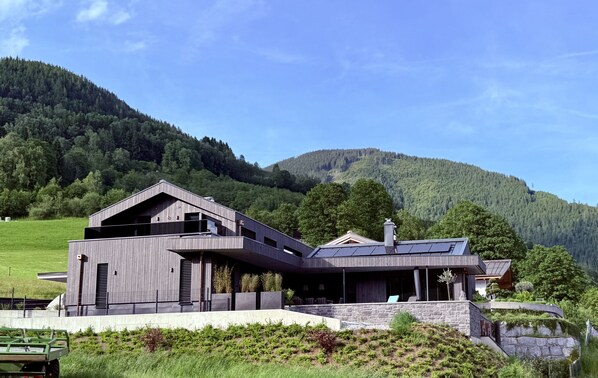 A modern house with a sloped roof, large windows, and a stone foundation.