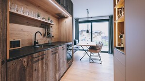 Eine moderne Küche mit Holzschränken, einer schwarzen Arbeitsplatte und einem Essbereich mit Tisch und Stühlen.