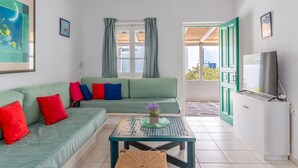 Una sala de estar con sofá, mesa de centro, televisor y puerta que da al exterior.