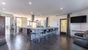 Una cocina moderna con una isla central, taburetes de bar y un televisor de pantalla plana montado en la pared.