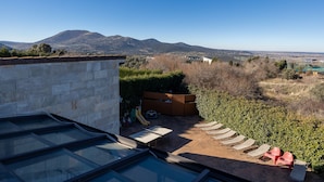 Una terraza en la azotea con vistas despejadas a montañas distantes, un muro de piedra y una zona de juegos con toboganes.