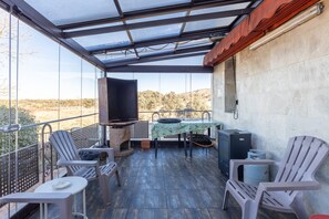 Un balcón con mesa, sillas, una parrilla y vistas al paisaje.