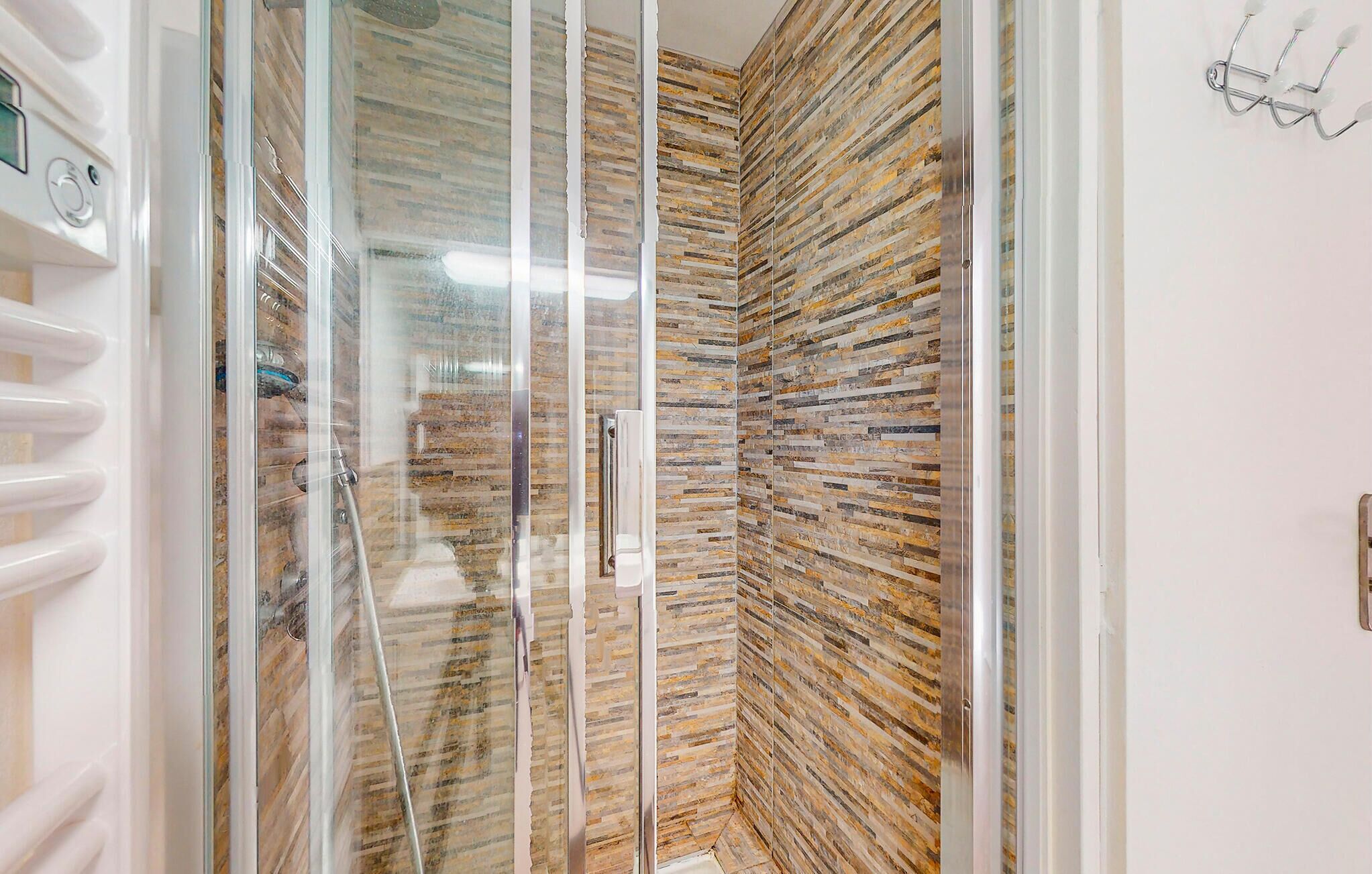 Una ducha con puerta de vidrio y pared con textura.