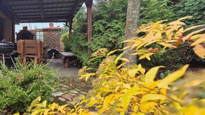 An outdoor patio area with a brick oven, wooden furniture, and lush greenery. - 2 bedroom beautiful apartment in Obryta (Obryta)