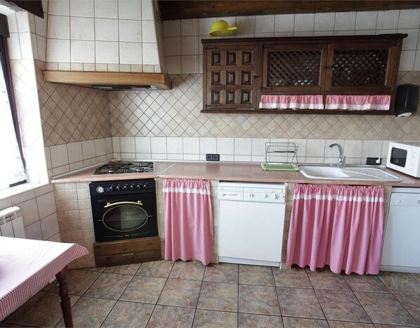 Une cuisine compacte équipée d’une cuisinière à gaz, d’un four, d’un lave-vaisselle et d’un four à micro-ondes.