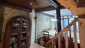 A rustic interior with a stone wall, wooden staircase, and a dining area with a table and chairs. - Casa Rural El Camino, Molinaseca, El Bierzo – Mountain Views & Terrace (Molinaseca)