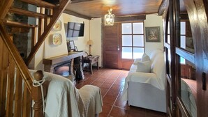 A rustic interior with a wooden staircase, a fireplace, a television, and a window with a view. - Casa Rural El Camino, Molinaseca, El Bierzo – Mountain Views & Terrace (Molinaseca)