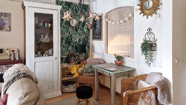 A cozy living room with a wicker sofa, a small table, and a pet bed.