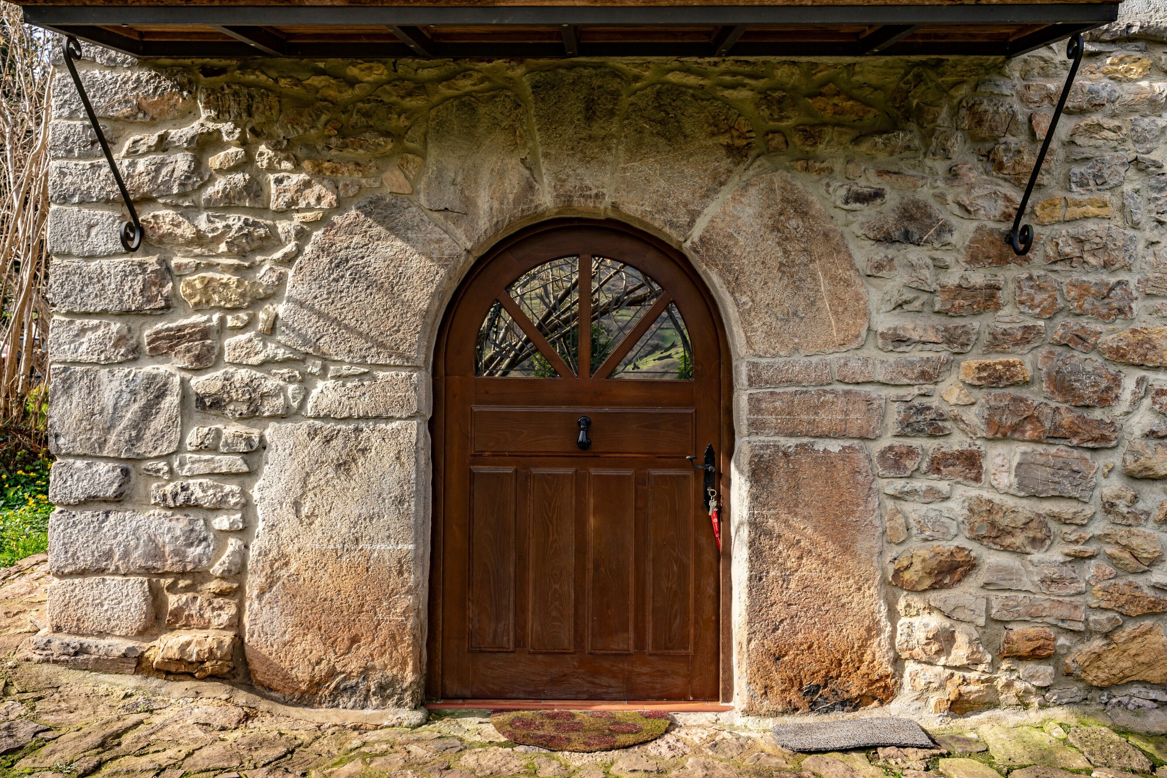 A stone building with a wooden door and an arched window.