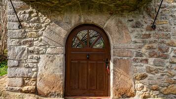A stone building with a wooden door and an arched window.