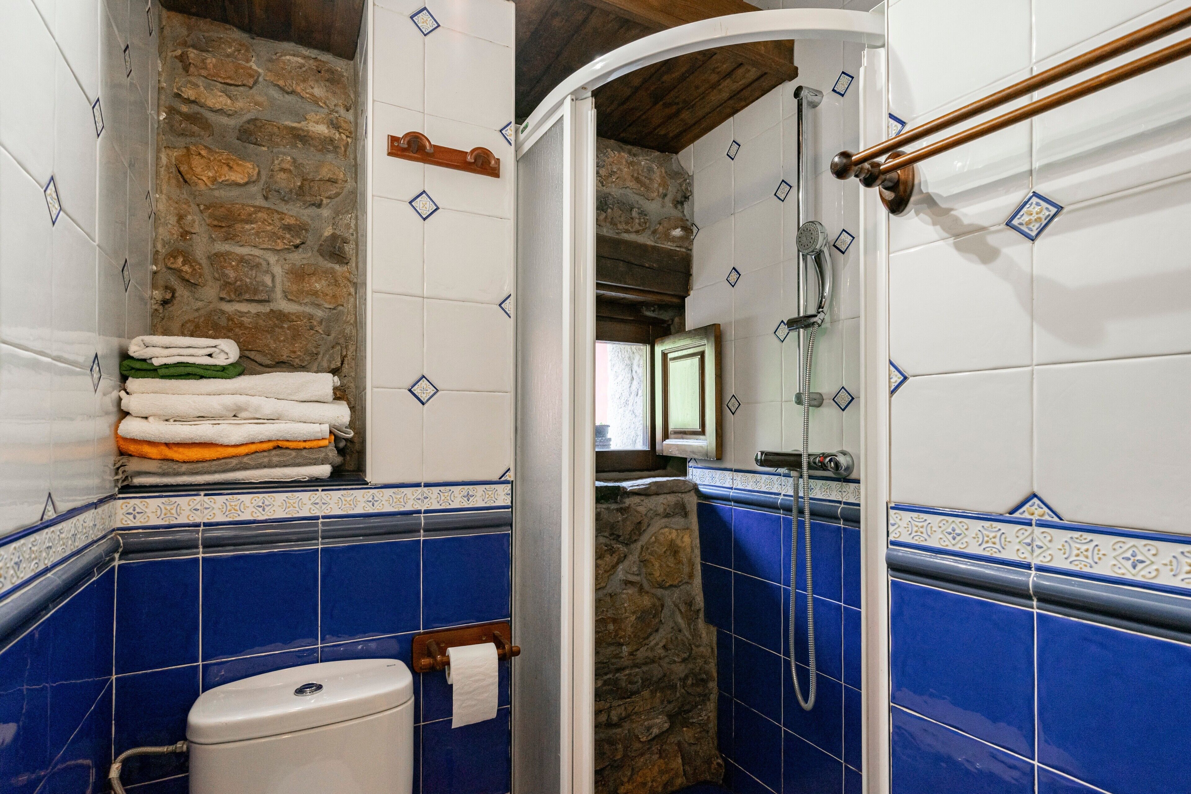 A bathroom with a stone wall, a toilet, a sink, and a shower.