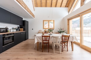A modern kitchen with dark cabinets, a wooden dining table, and chairs.