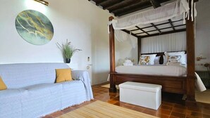A room with a four-poster bed, a sofa, a bench, a potted plant, and a wall painting. - Villa 'Ses Casetes Ibiza' with Mountain View, Wi-Fi and Air Conditioning (Illes Balears)