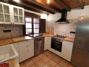 Een keuken met witte kastjes, een gasfornuis, een vaatwasser en een koelkast.
