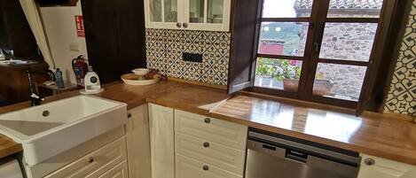 Una cocina con armarios blancos, lavavajillas y ventana con vistas al exterior.