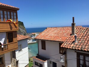 A coastal building with a tiled roof, a balcony with a yellow ribbon, and a view of the sea. - Holiday Home 'El Canto De Las Gaviotas' with Sea View, Balcony and Wi-Fi (Lastres)