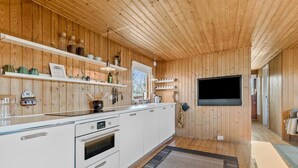 Een moderne keuken met houten lambrisering, witte kasten en een ingebouwde televisie.