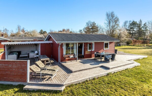 A red wooden house with a patio area featuring outdoor furniture and a table. - Nice home in Grenaa with WiFi (Grenaa)