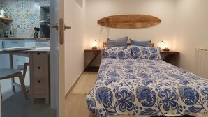 Une chambre à coucher avec un lit, des tables de chevet, une tête de lit en bois et une vue sur la cuisine.