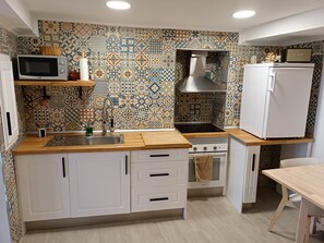 A kitchen with patterned tiles, a microwave, a sink, a stove, and a refrigerator.