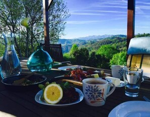 A table set outdoors with a scenic view, a plate of food, a cup of coffee, and a glass of water. - Country House 'Nela' with Mountain View, Private Terrace and Wi-Fi (Villaviciosa)