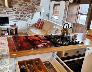 A kitchen with a gas stove, a kettle, a wooden countertop, and a stone wall. - Country House 'Nela' with Mountain View, Private Terrace and Wi-Fi (Villaviciosa)