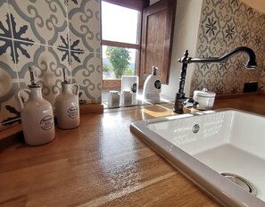 A kitchen with a white sink, wooden countertop, and decorative tiles. - Country House 'Nela' with Mountain View, Private Terrace and Wi-Fi (Villaviciosa)