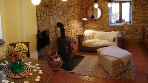 Una stanza accogliente con parete in pietra, camino, divano e televisore.