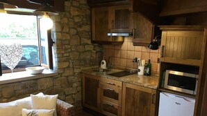 Una cucina accogliente con armadietti in legno, un muro in pietra, un forno a microonde integrato e una finestra con vista.