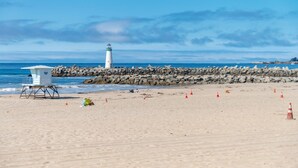 A beach with a lifeguard tower and a lighthouse in the background.