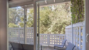 An outdoor patio with two metal chairs and a white wooden fence.