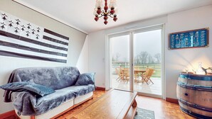 A modern living room with a sofa, a wooden coffee table, and a large sliding glass door leading to an outdoor patio. - 3 bedroom nice home in Arzal (Arzal)