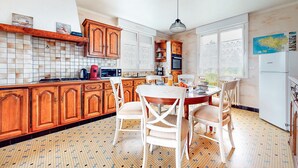 A kitchen with wooden cabinets, a tiled backsplash, a dining table with chairs, and a refrigerator. - 3 bedroom nice home in Arzal (Arzal)