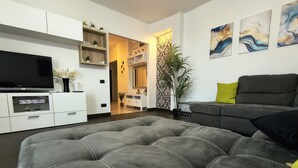 Una sala de estar moderna con un sofá gris, un televisor de pantalla plana y decoración mural.