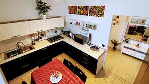 Una cocina moderna con una isla central, una mesa de comedor con mantel rojo y diversos electrodomésticos.