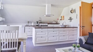 A spacious living area with a large white island kitchen, a dining table, and a sofa.