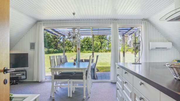 A modern kitchen with a dining area, large windows, and a view of the outdoors.