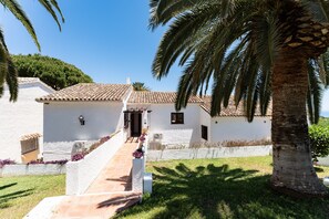 A white building with a tiled roof, a staircase leading to the entrance, and a palm tree in the foreground. - Holiday Home 'Feliz' with Sea View, Wi-Fi and Air Conditioning (Benalmadena)