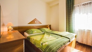 A hotel room with a bed, a nightstand, a lamp, and a window with curtains. - Awesome apartment in Kampor with sauna (Kampor)