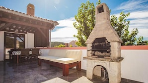 An outdoor patio with a stone oven, a covered seating area, and a view of the landscape. - Awesome apartment in Kampor with sauna (Kampor)