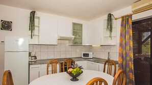 A compact kitchen with white cabinets, a microwave, a refrigerator, and a dining table with chairs. - Awesome apartment in Kampor with sauna (Kampor)