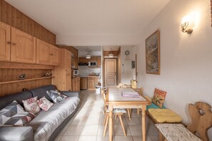 A cozy living room with a sofa, a dining table, and wooden cabinets. - Apartment "Vue Mont Blanc" (Saint-Gervais-les-Bains)