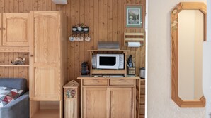 A compact room with wooden walls, a microwave, a small shelf with cups, and a mirror. - Apartment "Vue Mont Blanc" (Saint-Gervais-les-Bains)