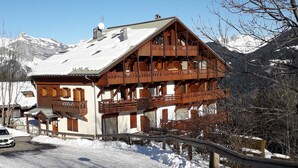 A chalet-style building with a balcony, a snow-covered roof, and a mountainous backdrop. - Apartment "Vue Mont Blanc" (Saint-Gervais-les-Bains)