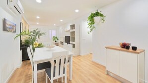 Une cuisine moderne avec des meubles blancs, un plan de travail en bois et une plante suspendue.