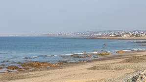 A coastal beach with a clear view of the sea and distant buildings. - Holiday Home 'Grande Maison À 5min Des Plages' with Shared Pool, Terrace and Private Garden (Pouldreuzic)